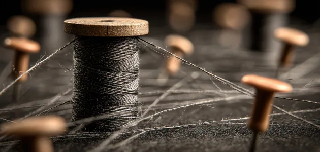 Spool of thread with strands radiating out to wooden pins