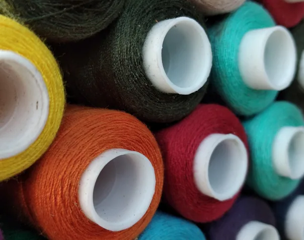 Colourful industrial thread cones packed together, seen from the ends
